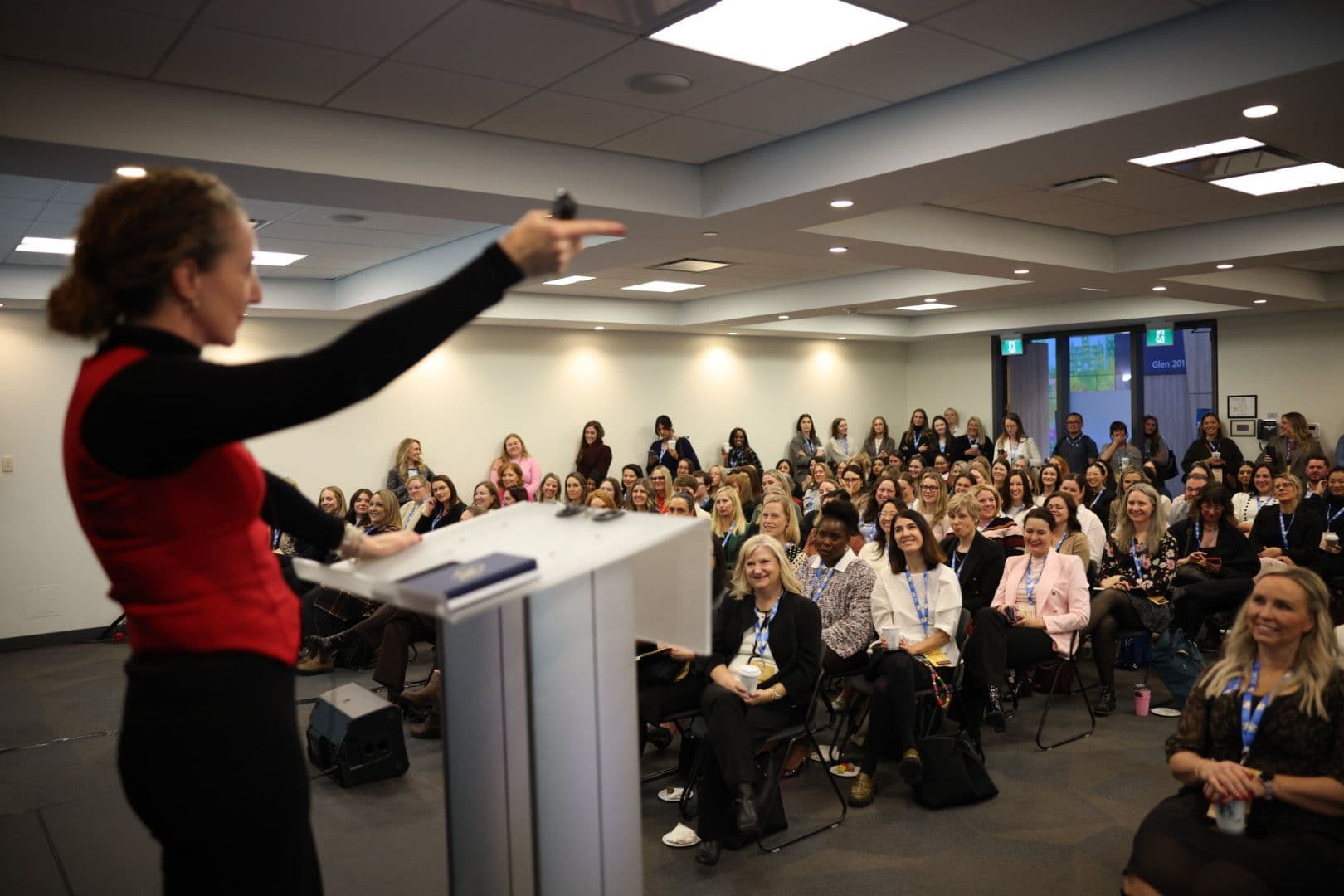 Speaker addressing a large audience from a podium