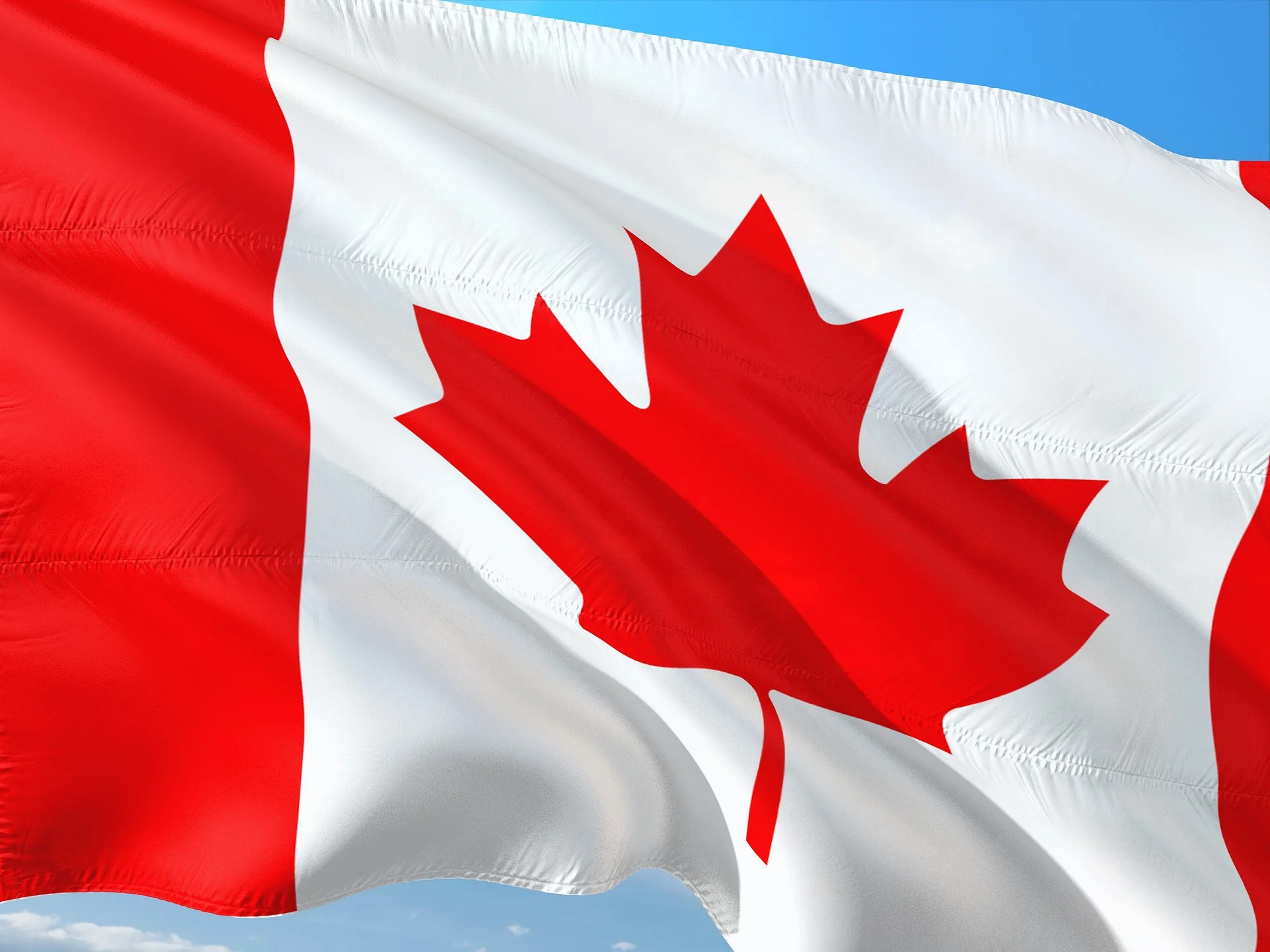 Canadian maple leaf flag flying against a blue sky