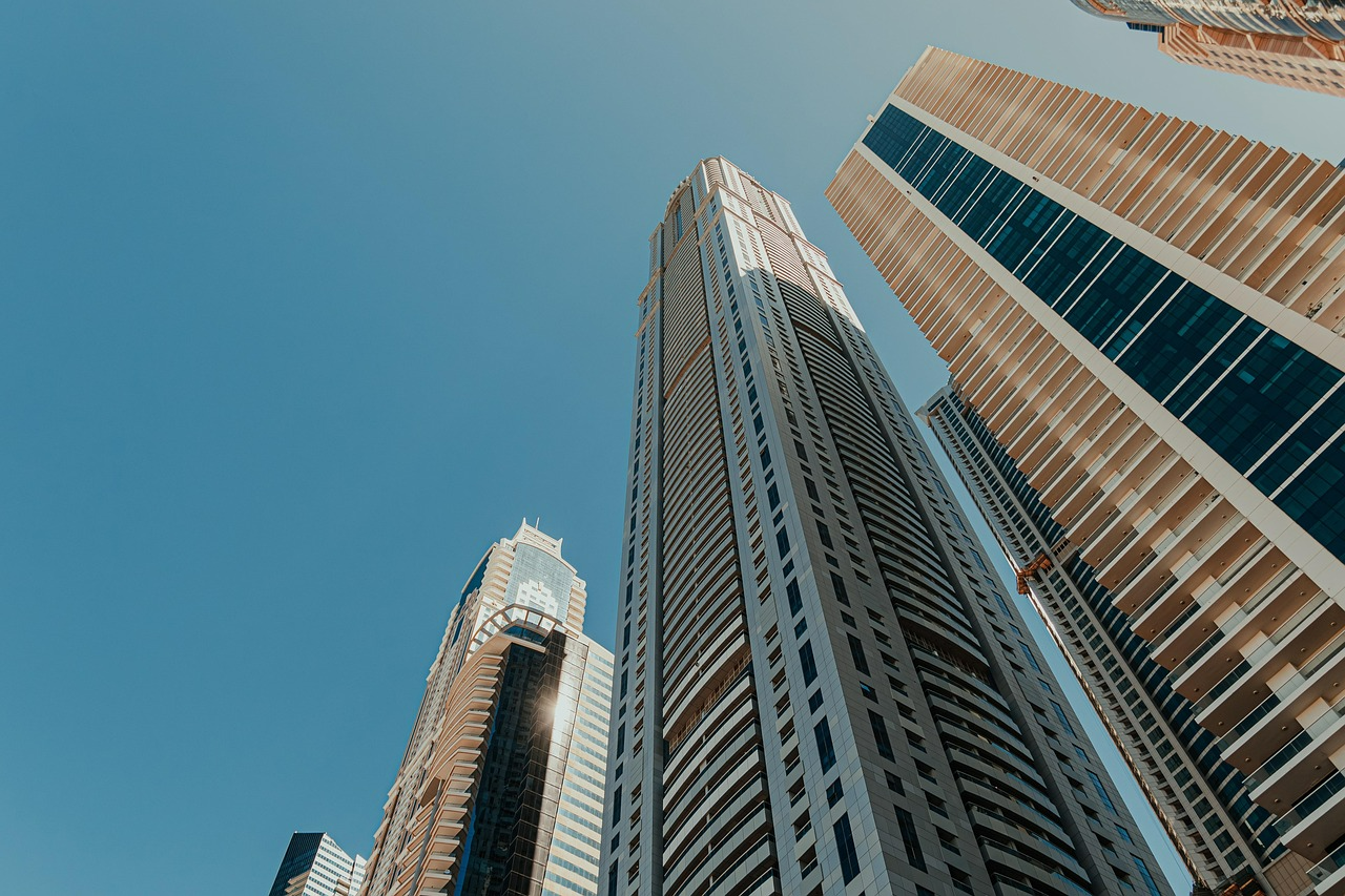Looking up at modern high-rise buildings against a blue sky