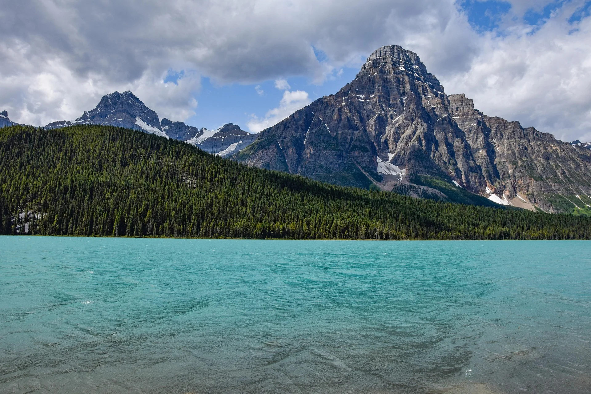 Turquoise mountain lake beneath rocky peaks and a forested shoreline
