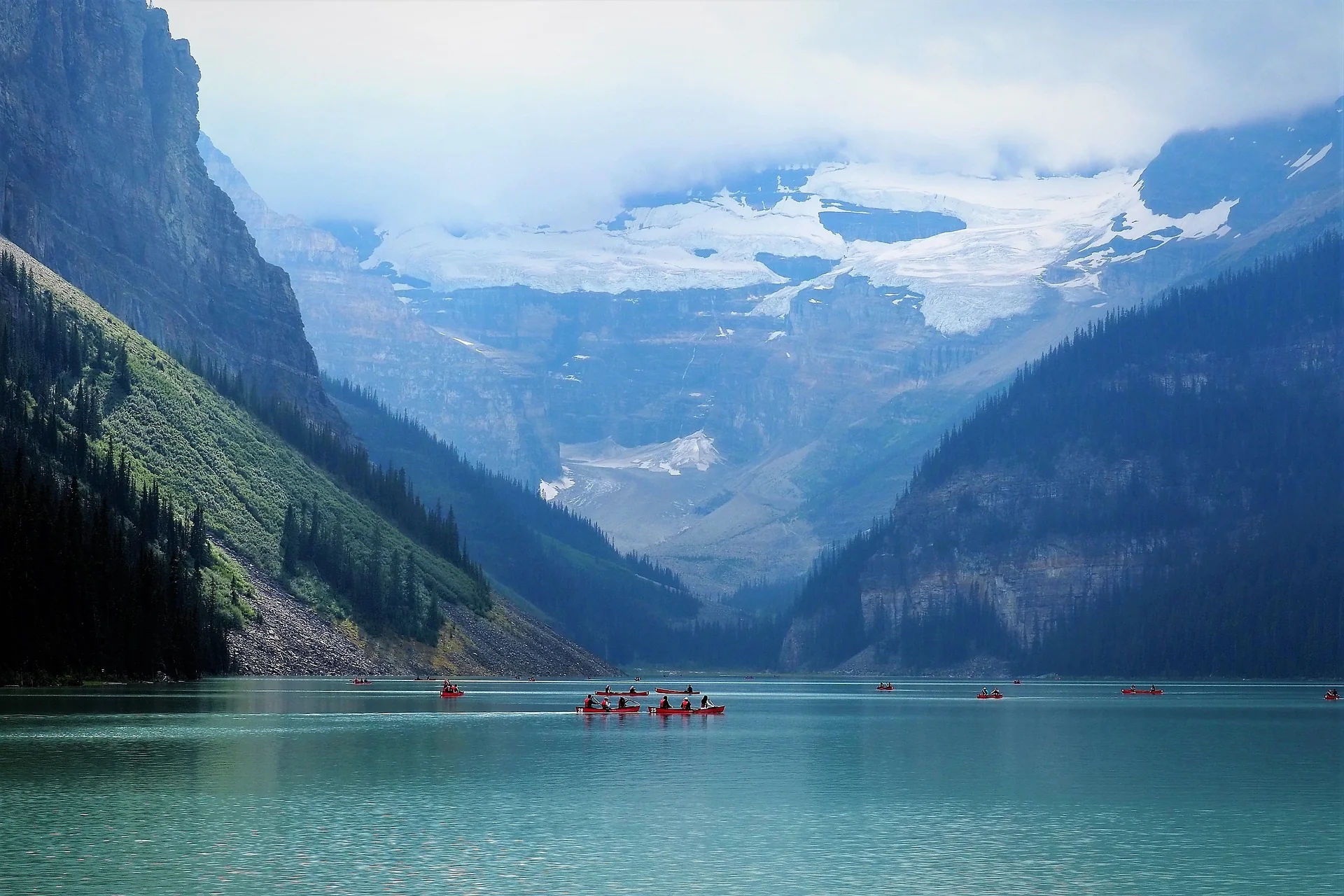 Canoes on Lake Louise beneath mountains and a glacier