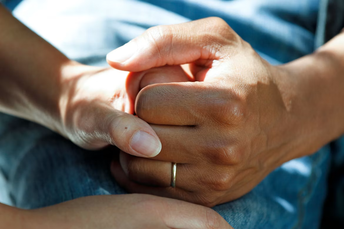 One person holding another person’s hands in support